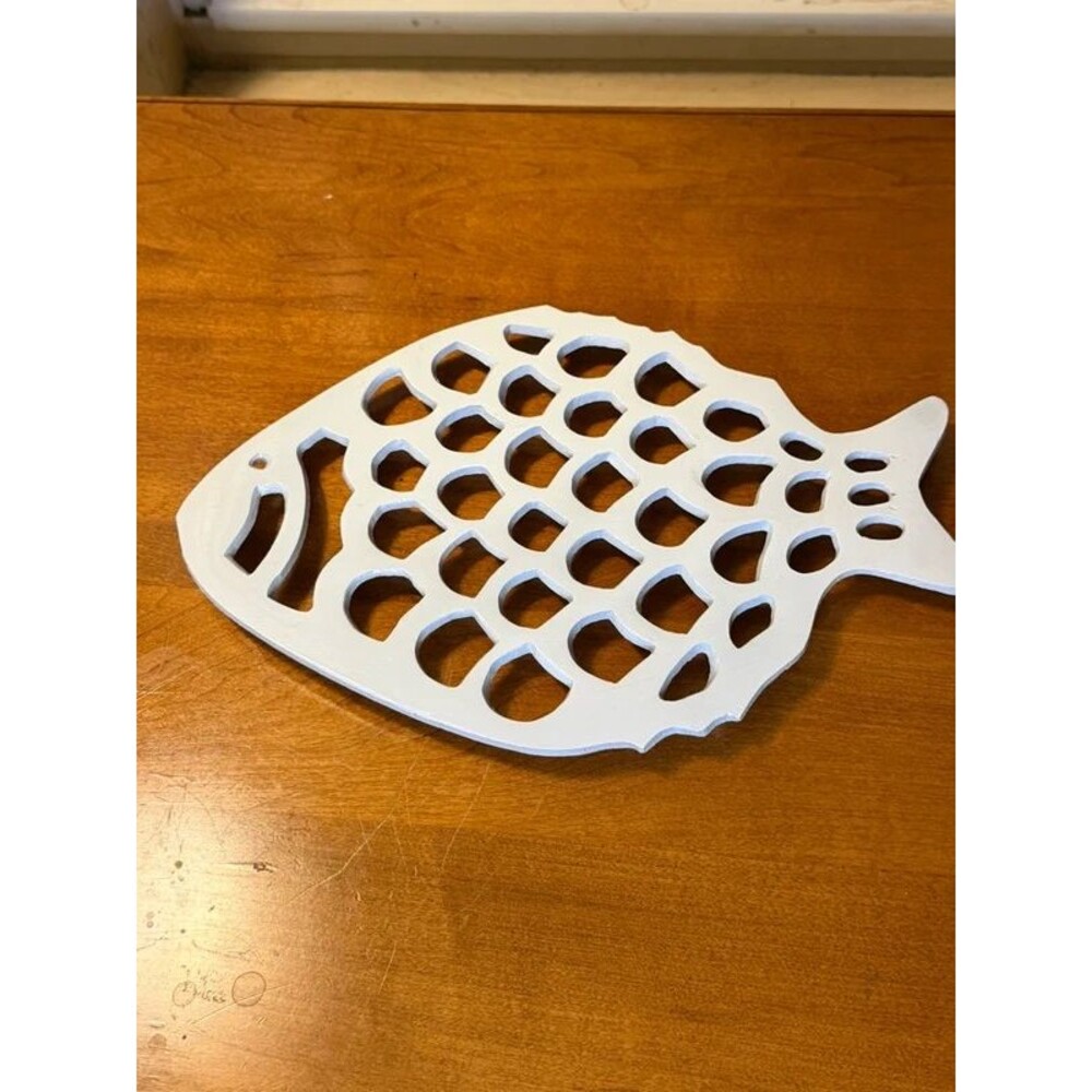 White fish-shaped metal trivet with circular cutouts